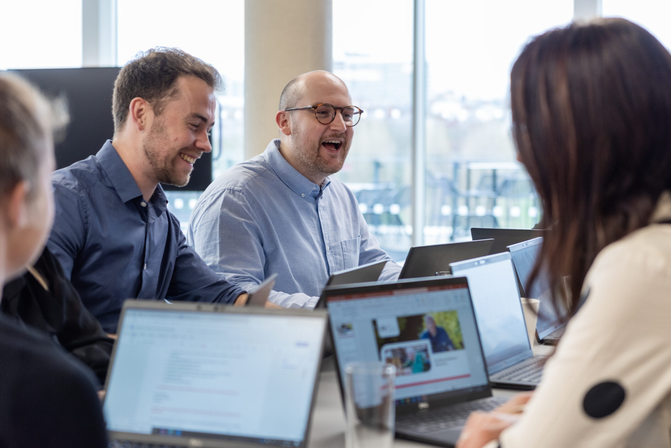 Group of people sitting at desk looking at laptops.