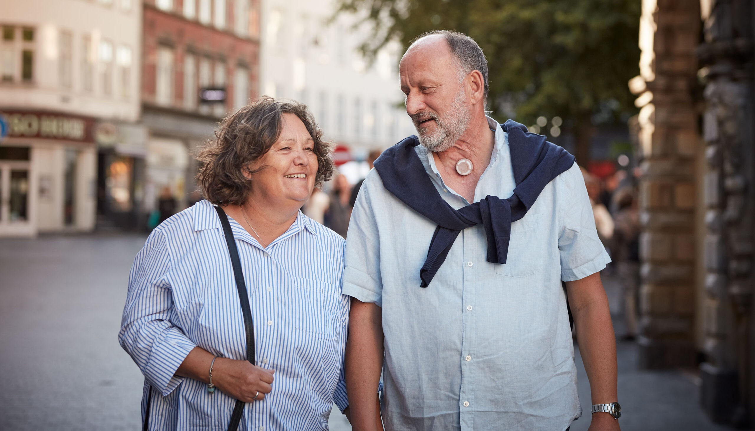 man with a neck stoma walking on street with woman and using provox life protect hme